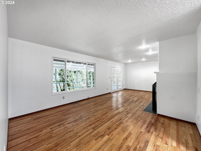 unfurnished living room with a textured ceiling and wood-type flooring