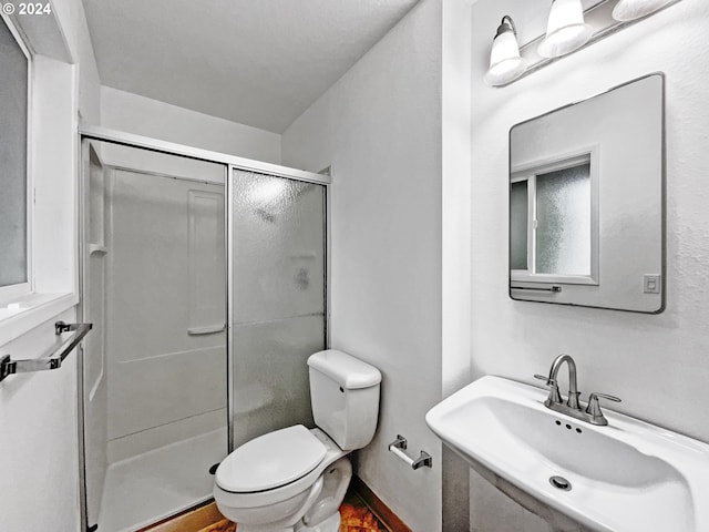 bathroom with toilet, a shower with shower door, and sink