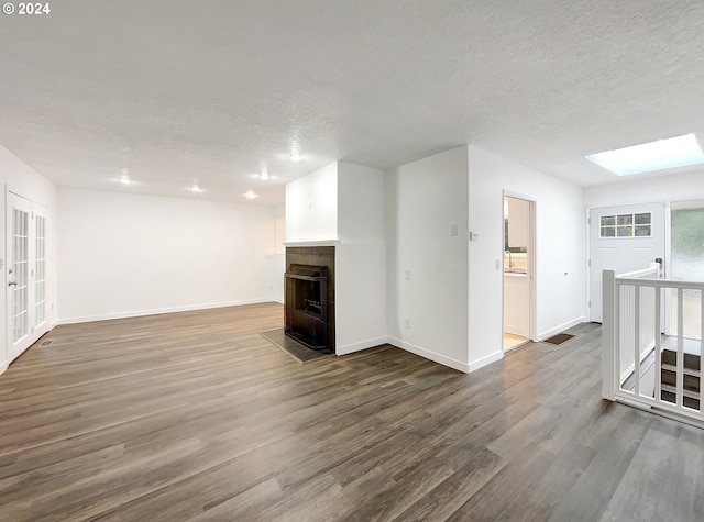 unfurnished living room featuring hardwood / wood-style floors, a textured ceiling, and a skylight