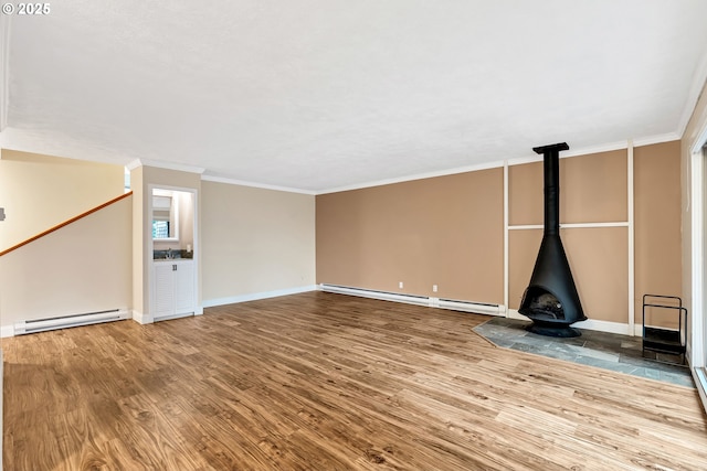 unfurnished living room featuring hardwood / wood-style floors, a wood stove, a baseboard heating unit, and crown molding