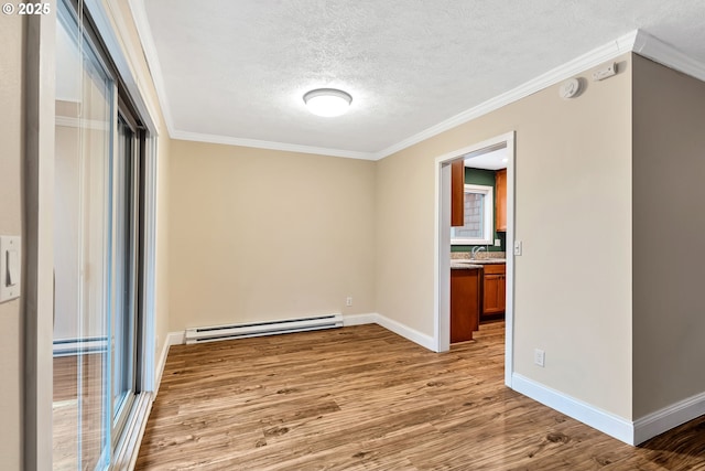 empty room with sink, light hardwood / wood-style flooring, ornamental molding, a textured ceiling, and baseboard heating