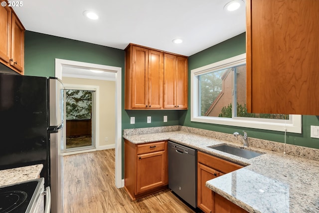 kitchen with light stone counters, ornamental molding, stainless steel appliances, sink, and light hardwood / wood-style flooring