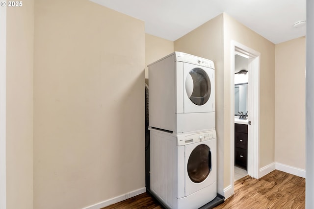 washroom featuring stacked washer and dryer, hardwood / wood-style flooring, and sink