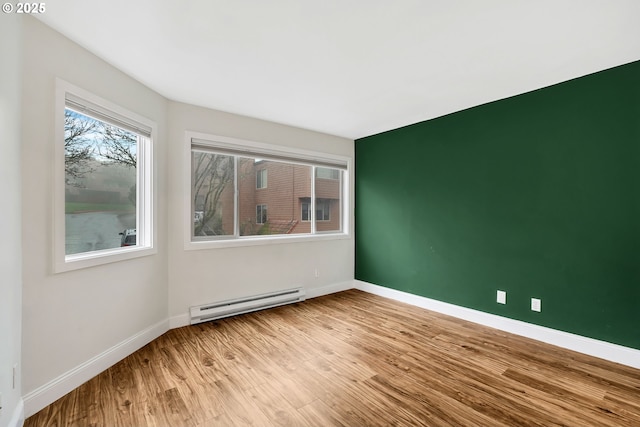 spare room with baseboard heating and light hardwood / wood-style flooring