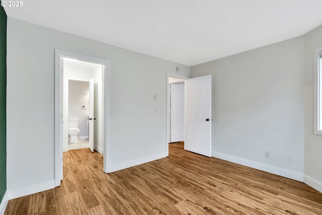 unfurnished bedroom with ensuite bathroom and light hardwood / wood-style floors