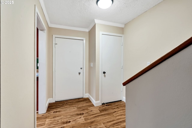 entrance foyer with a textured ceiling, light wood-type flooring, and crown molding