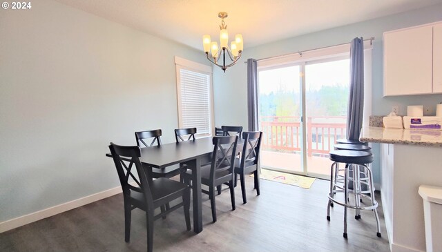 dining area with dark wood-type flooring and an inviting chandelier