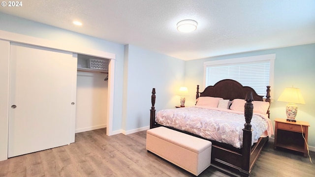 bedroom with a textured ceiling, light wood-type flooring, and a closet