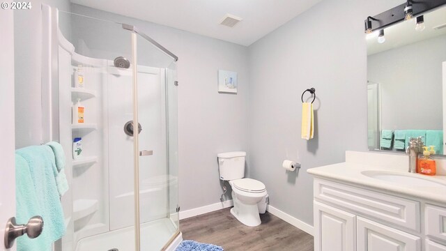 bathroom featuring vanity, hardwood / wood-style flooring, a shower with shower door, and toilet