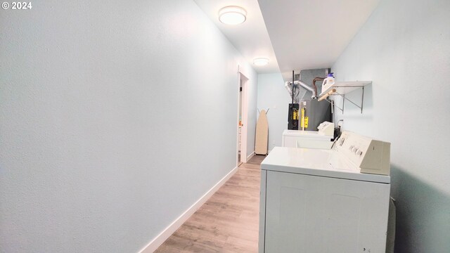 clothes washing area featuring washer and dryer, light hardwood / wood-style floors, and water heater