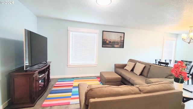 living room with an inviting chandelier, a baseboard radiator, a textured ceiling, and light hardwood / wood-style flooring