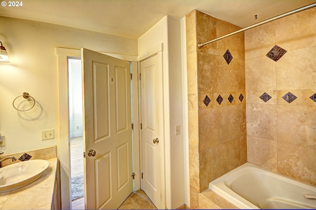 bathroom with tiled shower / bath, a textured ceiling, tile floors, and vanity