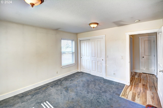 unfurnished bedroom with dark hardwood / wood-style flooring, a closet, and a textured ceiling