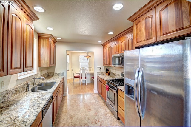 kitchen with light tile floors, light stone countertops, a textured ceiling, appliances with stainless steel finishes, and sink