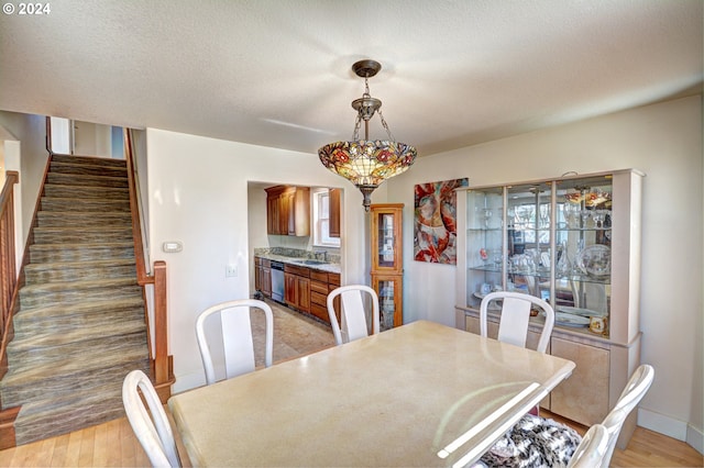 dining room featuring a textured ceiling, sink, and light hardwood / wood-style flooring