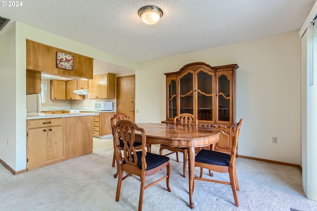 dining space with light carpet and a textured ceiling