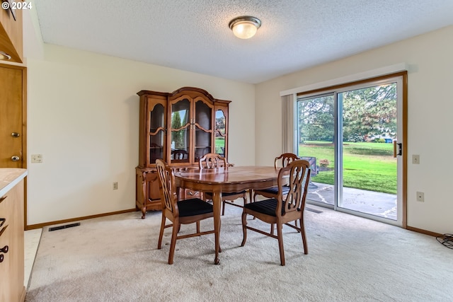 dining area featuring light colored carpet and a textured ceiling