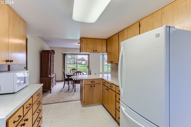 kitchen with kitchen peninsula, light carpet, and white appliances