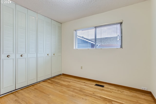 unfurnished bedroom with a closet, a textured ceiling, and light hardwood / wood-style flooring