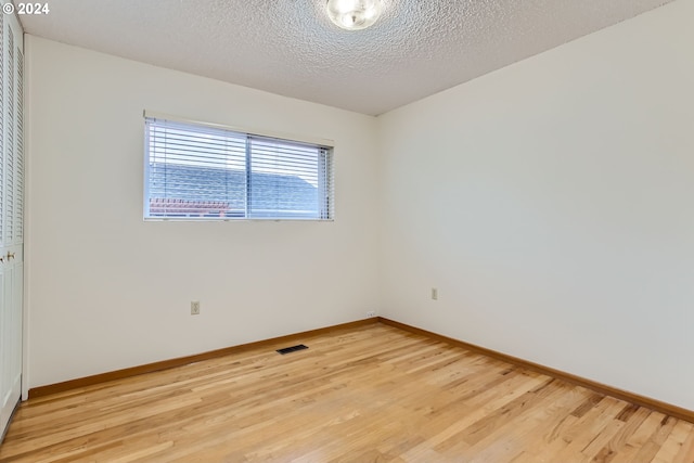 spare room featuring light wood-type flooring and a textured ceiling