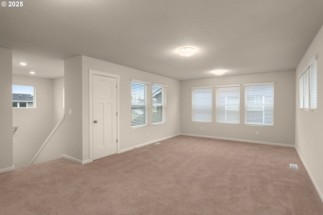 carpeted empty room with a textured ceiling