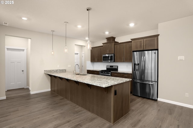 kitchen with a kitchen breakfast bar, stainless steel appliances, pendant lighting, sink, and kitchen peninsula