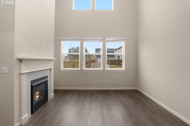 unfurnished living room featuring dark hardwood / wood-style flooring and a towering ceiling