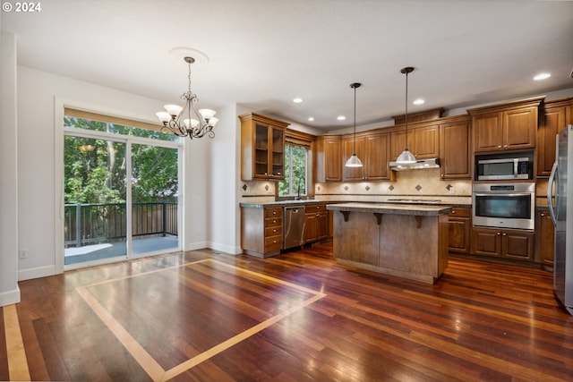 kitchen featuring a kitchen island, dark hardwood / wood-style floors, decorative light fixtures, decorative backsplash, and stainless steel appliances