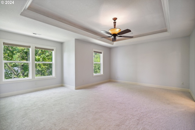 unfurnished room featuring ceiling fan, a tray ceiling, and light carpet