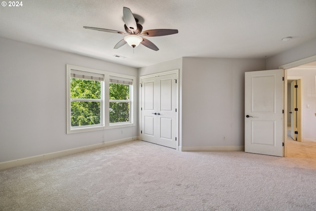 unfurnished bedroom featuring light carpet, ceiling fan, and a closet