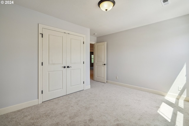 unfurnished bedroom with light carpet and a closet