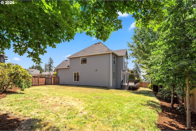 rear view of property with a wooden deck and a yard