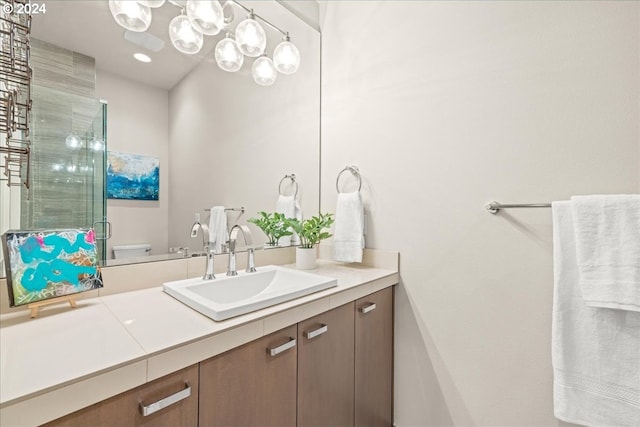 bathroom with toilet, an inviting chandelier, and vanity