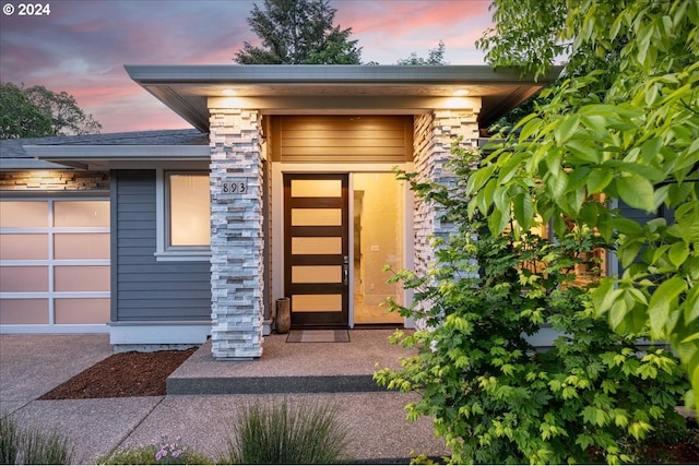 exterior entry at dusk featuring a garage