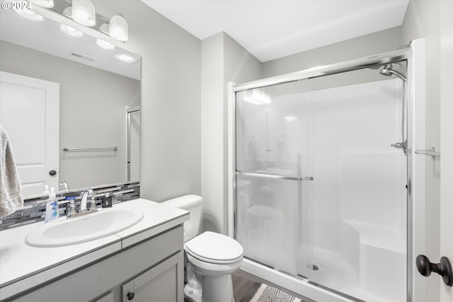 bathroom featuring vanity, toilet, and a shower with door