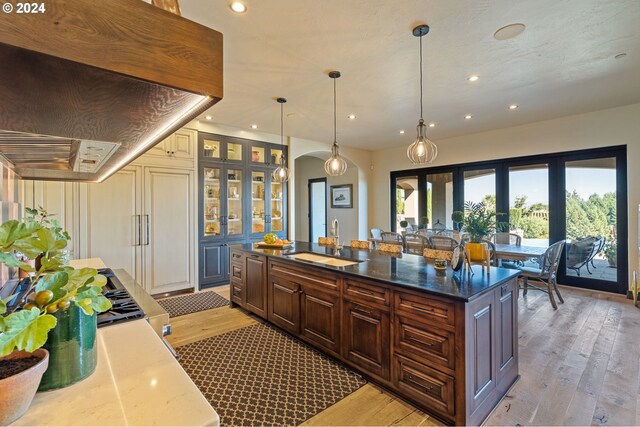 26590 SW French Oak Dr, West Linn, OR 97068 - kitchen with arched walkways, ventilation hood, a sink, and light wood finished floors