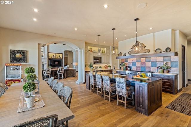 26590 SW French Oak Dr, West Linn, OR 97068 - kitchen featuring a spacious island, a breakfast bar, light wood-type flooring, arched walkways, and ornate columns