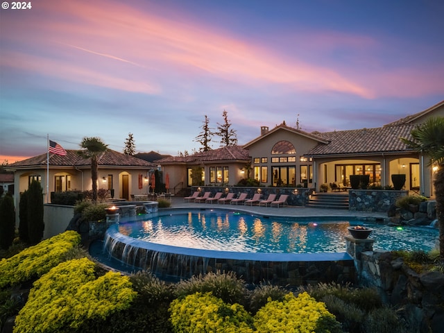 26590 SW French Oak Dr, West Linn, OR 97068 - back of house at dusk with a tile roof, stucco siding, a pool with connected hot tub, and a patio area