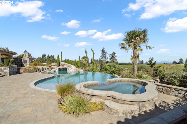 view of swimming pool with an in ground hot tub, a water slide, and a patio area