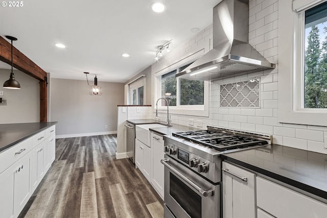 kitchen featuring wall chimney exhaust hood, dark hardwood / wood-style floors, decorative light fixtures, white cabinets, and appliances with stainless steel finishes