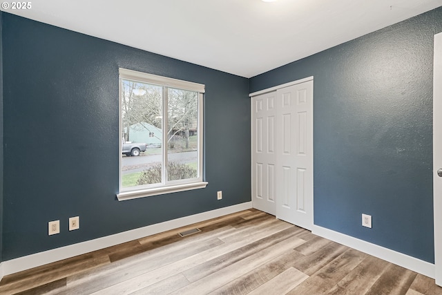 unfurnished bedroom featuring light hardwood / wood-style floors and a closet