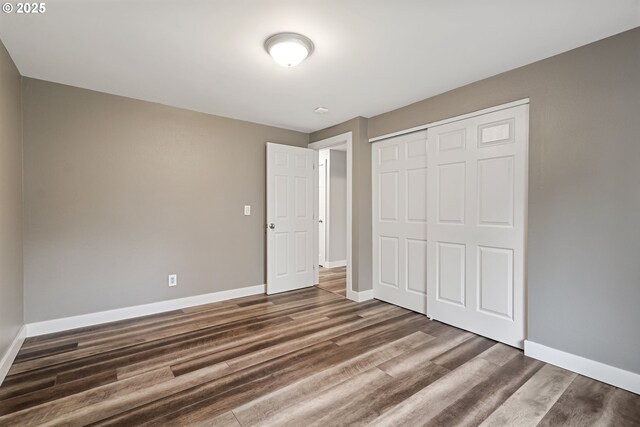 unfurnished bedroom with a closet and dark hardwood / wood-style floors