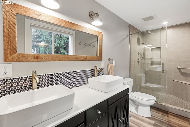 bathroom featuring decorative backsplash, vanity, a shower with door, hardwood / wood-style flooring, and toilet