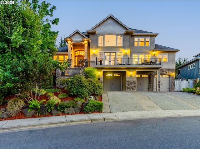 view of front of home with concrete driveway, an attached garage, fence, a balcony, and stone siding