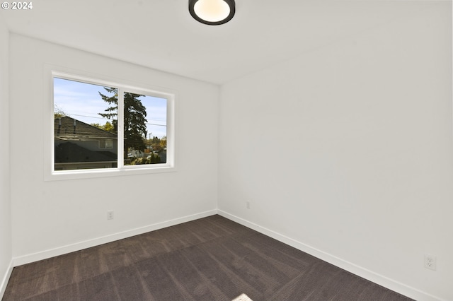 spare room featuring dark colored carpet