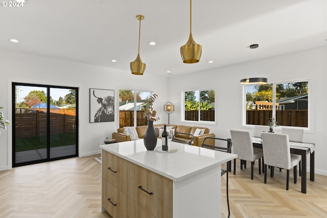 kitchen featuring pendant lighting, light parquet flooring, a center island, and plenty of natural light