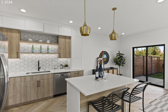 kitchen featuring white cabinetry, sink, stainless steel appliances, tasteful backsplash, and decorative light fixtures