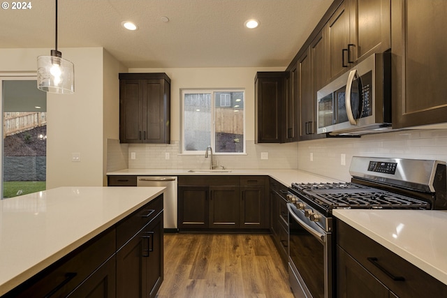 kitchen featuring sink, dark hardwood / wood-style floors, plenty of natural light, decorative light fixtures, and appliances with stainless steel finishes