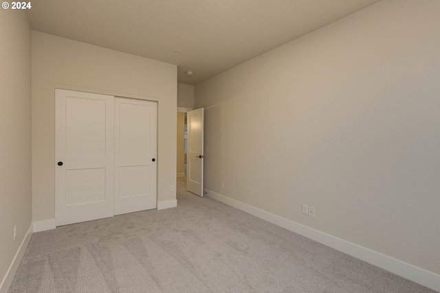 unfurnished bedroom featuring a closet and light colored carpet