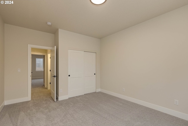 unfurnished bedroom featuring a closet and light colored carpet